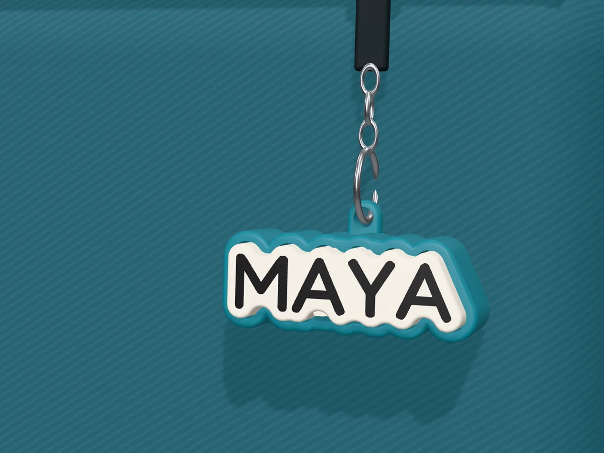 Customized clicker keychain reading MAYA hanging from a backpack zip