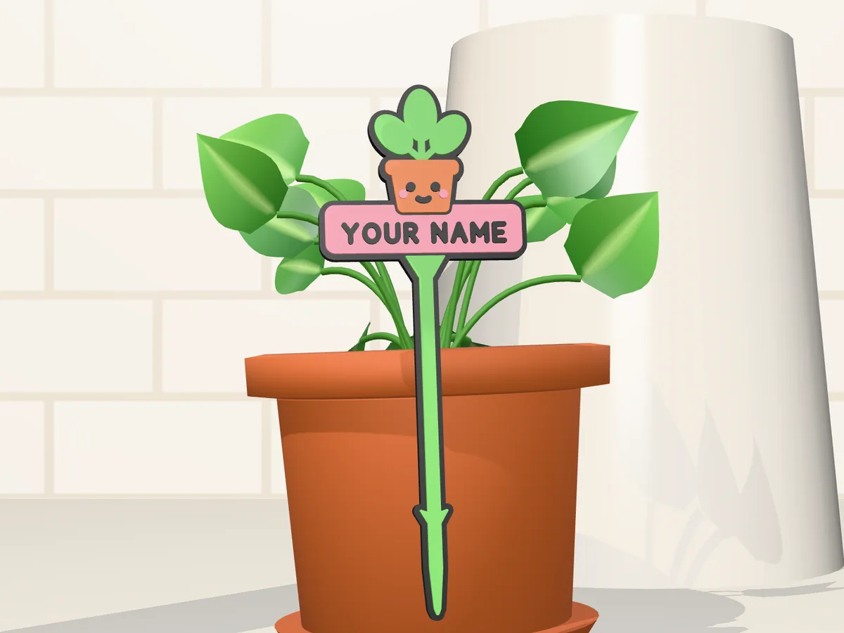 Plant buddy stake with a green leafy character and a YOUR NAME plate in a terracotta pot